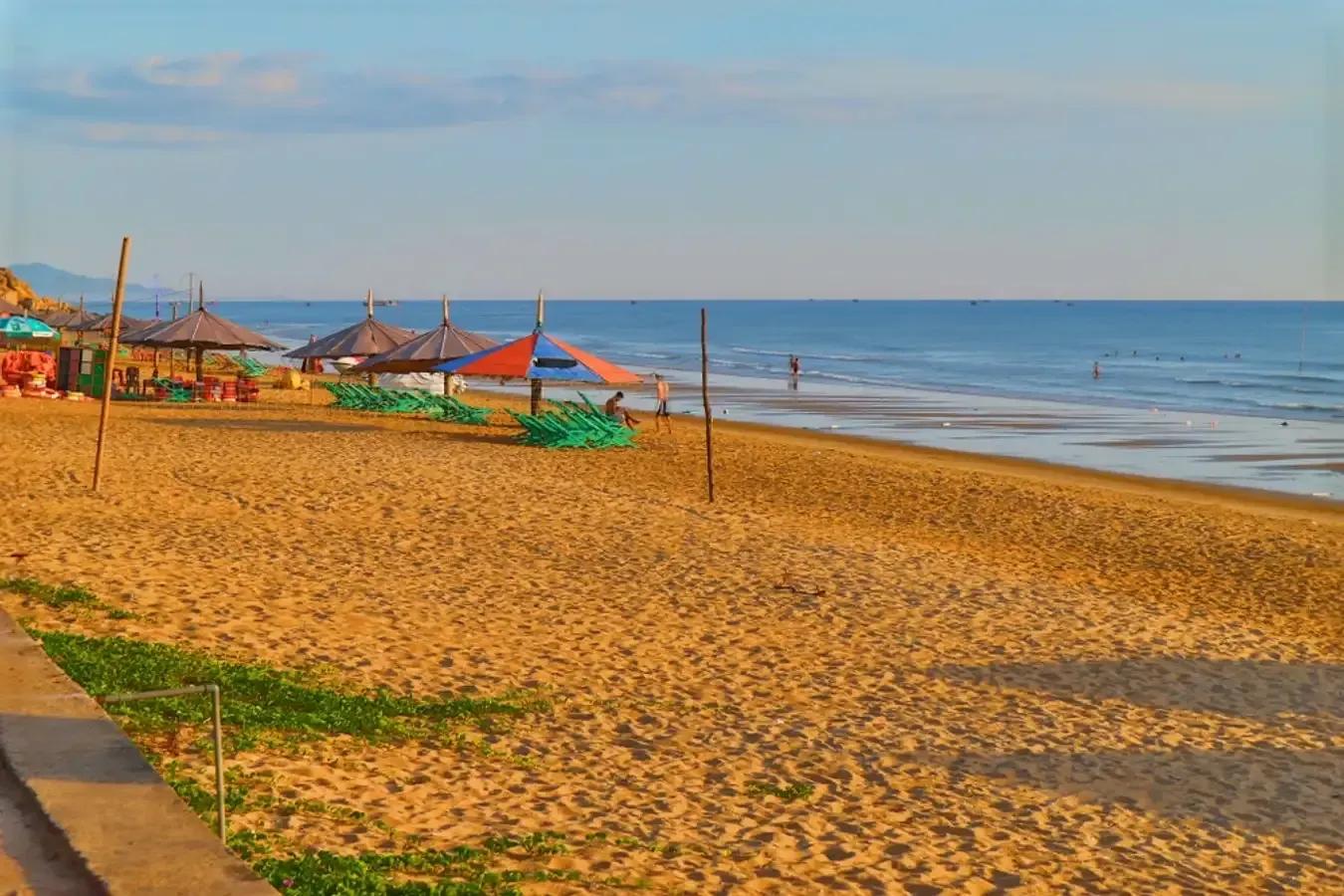 Fine golden beach with colorful parasols shading the area.