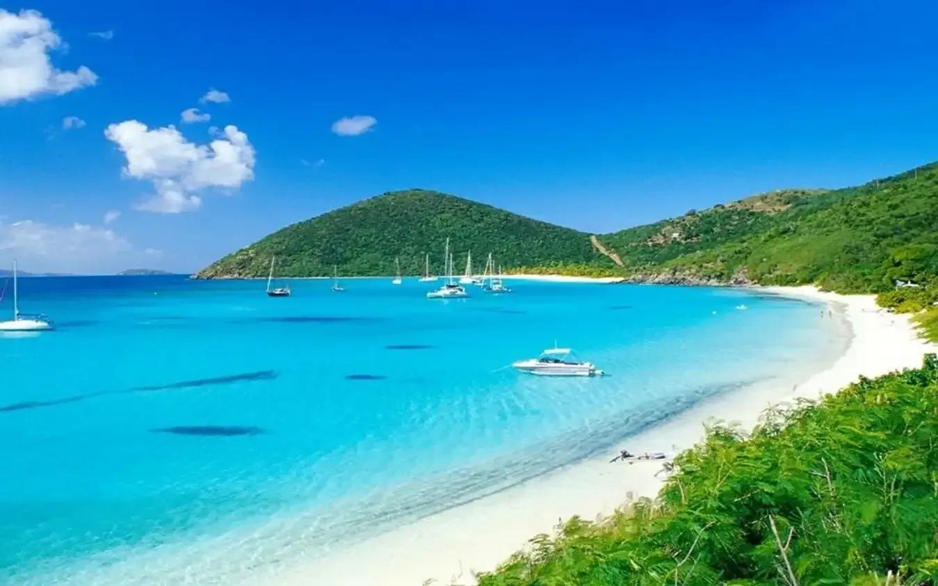 The beach boasts crystal-clear waters with peacefully anchored boats.