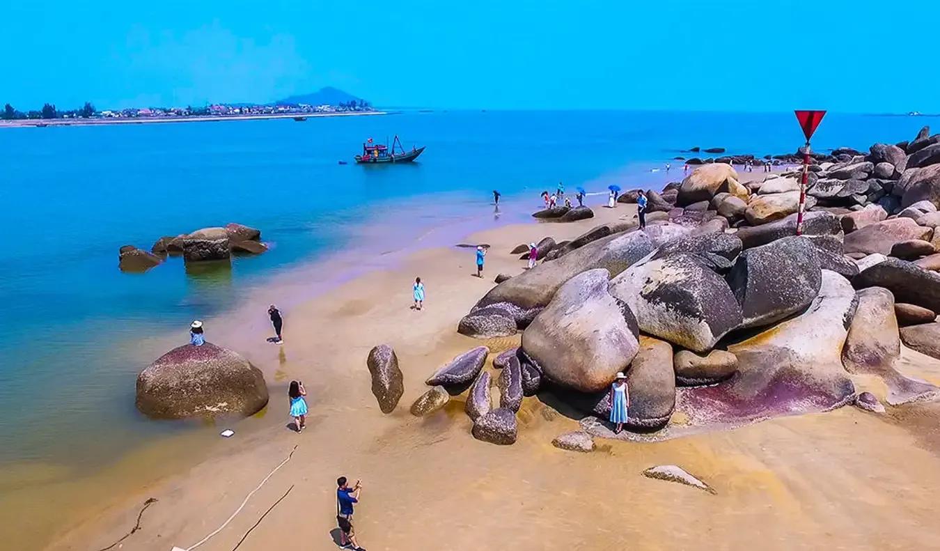 A beach with natural rock formations and visitors enjoying the view.