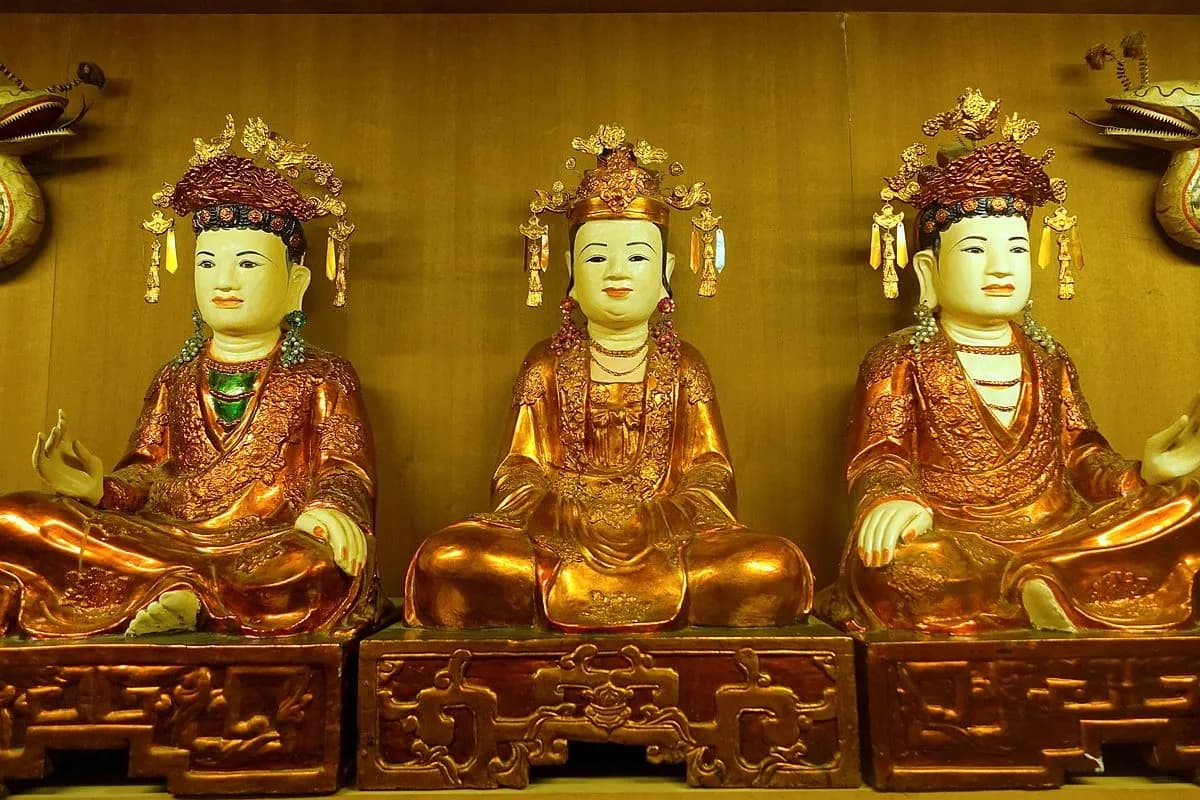 Three golden Buddhas glisten in the solemn atmosphere of Phủ Dầy.