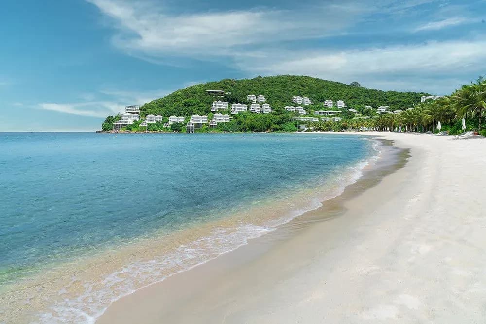 Long shoreline with azure waters and a distant resort.  