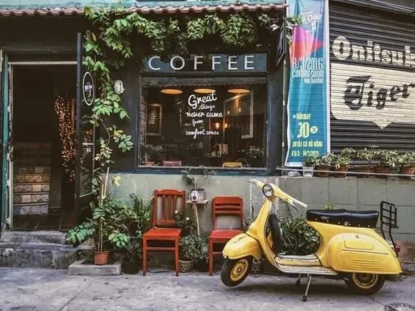 A vintage coffee shop with a yellow Vespa parked at the entrance.