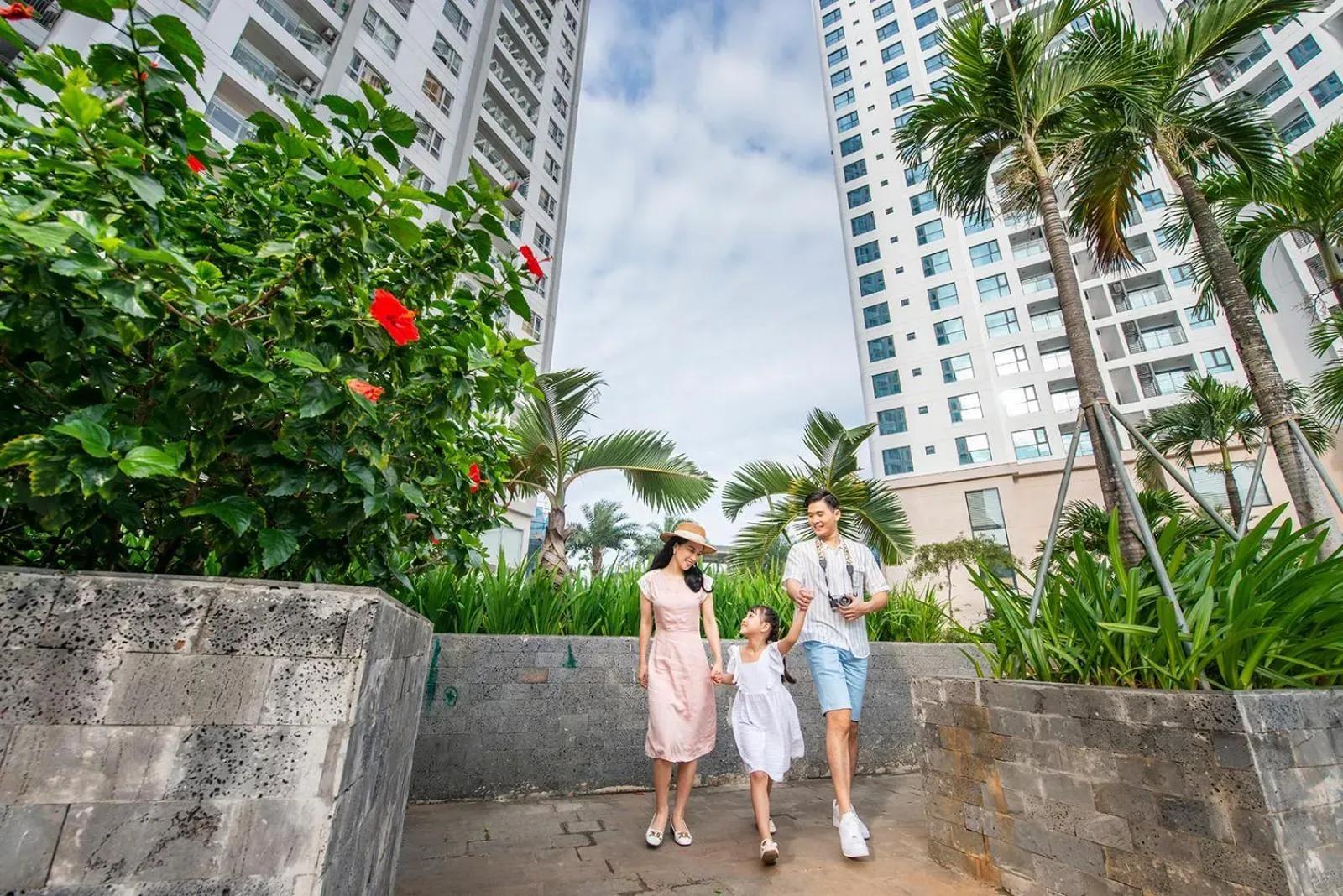 A happy family strolls under lush tropical trees in the hotel gardens.