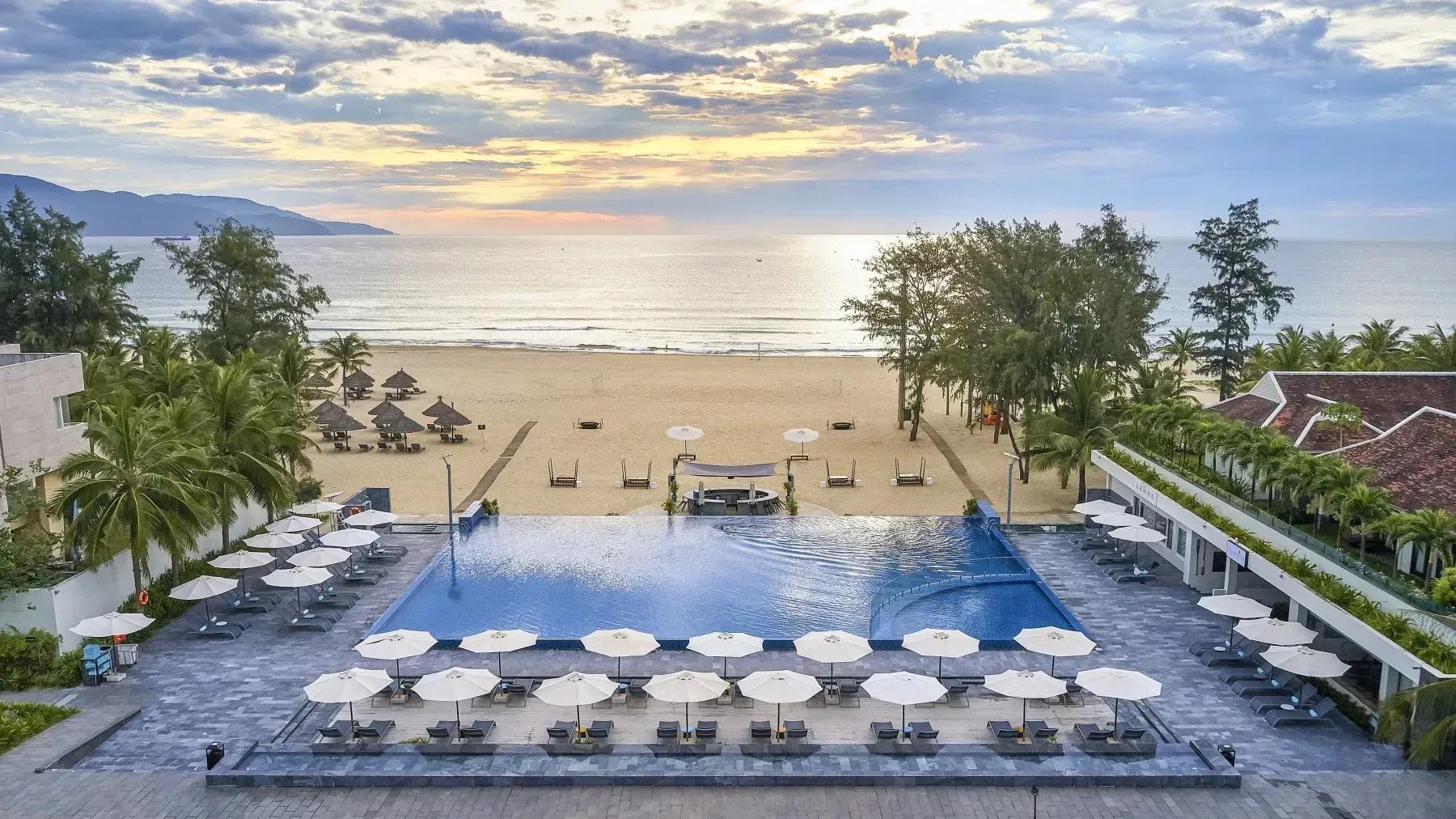Infinity pool by the beach with sun loungers and parasols.