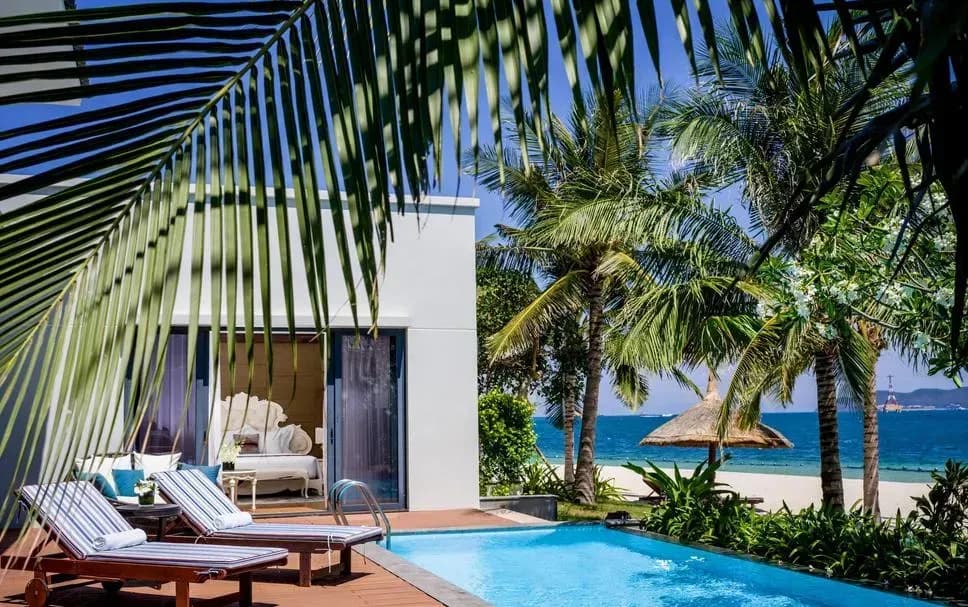 Villa with a private pool by the beach, surrounded by palm trees and ocean view.