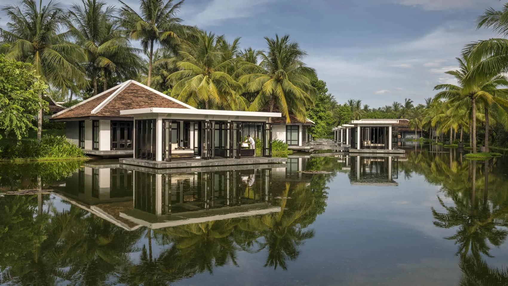 A serene view of Four Seasons Resort Hoi An, featuring luxurious villas surrounded by lush gardens and overlooking a tranquil river
